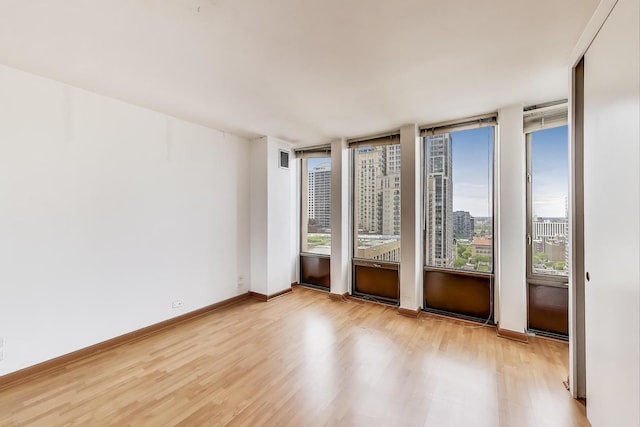 100 E Walton St Unit 25F, Chicago, IL 60611 - spare room with wood finished floors, plenty of natural light, a city view, and baseboards