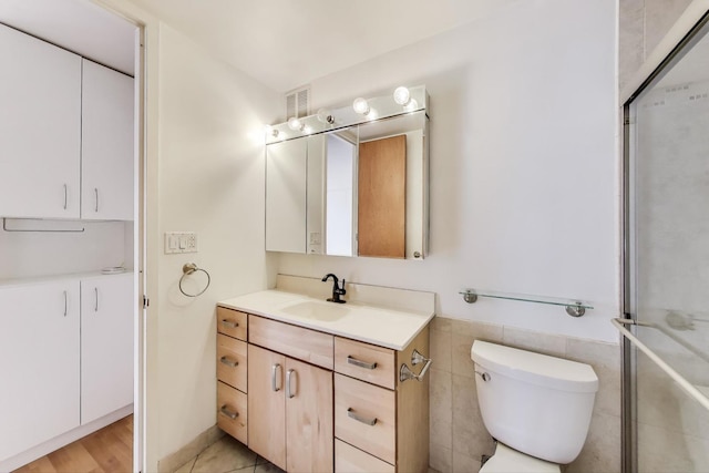 100 E Walton St Unit 25F, Chicago, IL 60611 - bathroom featuring vanity, toilet, tile walls, an enclosed shower, and wainscoting