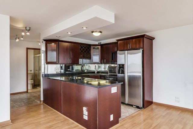 100 E Walton St Unit 25F, Chicago, IL 60611 - kitchen with appliances with stainless steel finishes, dark countertops, glass insert cabinets, a sink, and a peninsula
