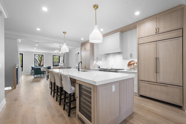 kitchen featuring paneled fridge, wine cooler, a large island, a sink, and open floor plan