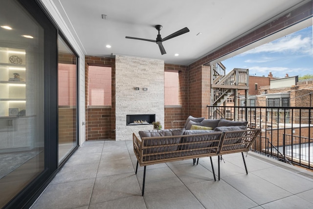 balcony with ceiling fan and an outdoor living space with a fireplace