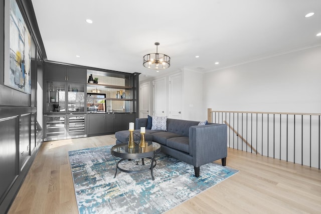 living room featuring ornamental molding, a chandelier, light wood-style floors, and recessed lighting