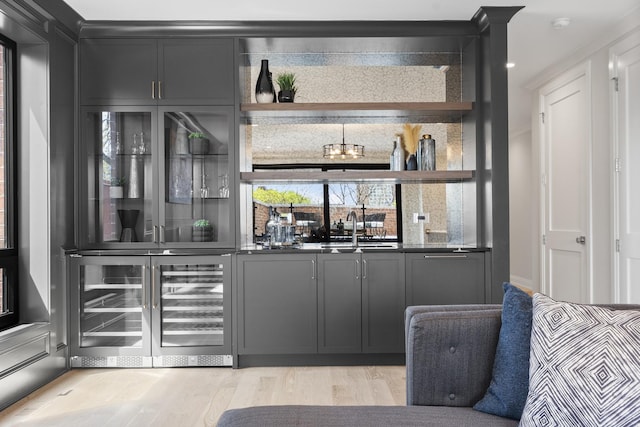 indoor wet bar featuring wine cooler and light wood-style floors