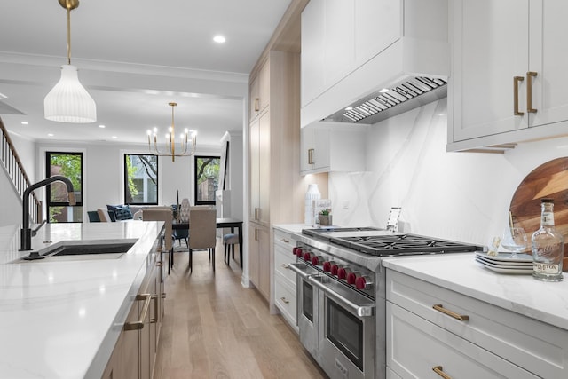 kitchen featuring range with two ovens, a sink, light wood finished floors, premium range hood, and light stone countertops