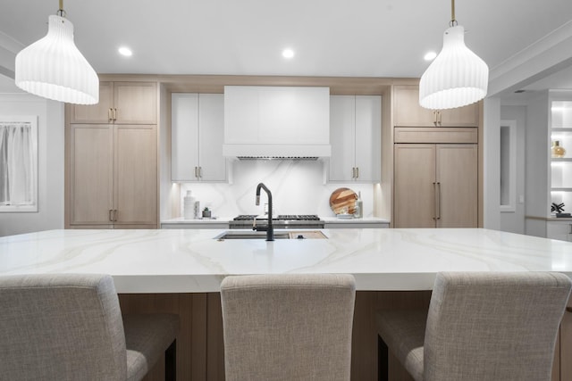 kitchen featuring custom range hood, recessed lighting, light stone counters, a large island, and a sink