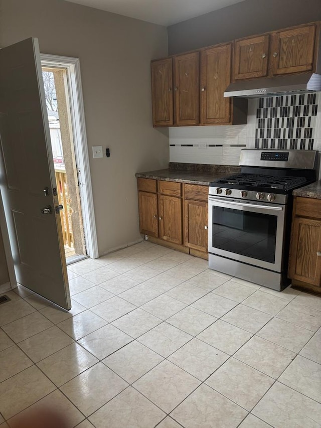 7941 S Woodlawn Ave, Chicago, IL 60619 - kitchen with gas stove, decorative backsplash, extractor fan, dark countertops, and light tile patterned floors