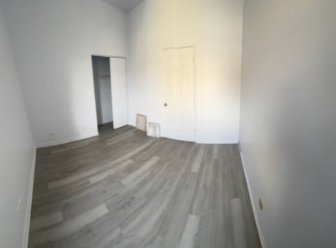 7941 S Woodlawn Ave, Chicago, IL 60619 - unfurnished bedroom featuring wood finished floors, a closet, and baseboards