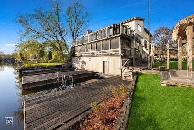dock with stairway, a yard, and a deck with water view