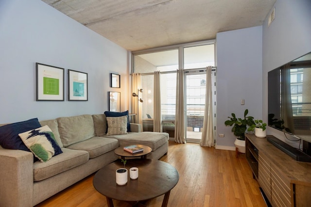 living room with light wood-style flooring, a wall of windows, and baseboards