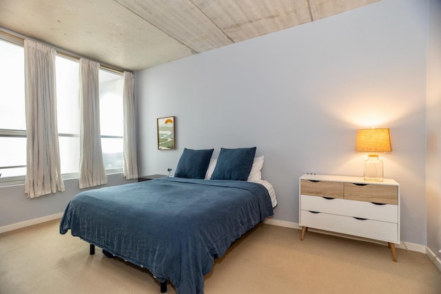 bedroom with baseboards and light colored carpet