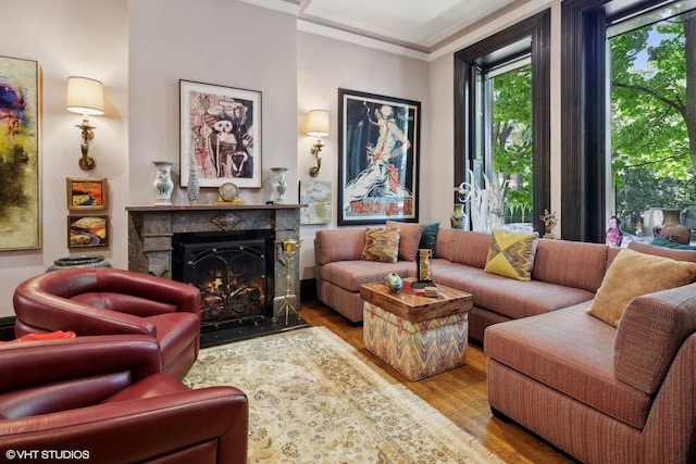 living room featuring wood finished floors, a fireplace with flush hearth, and ornamental molding