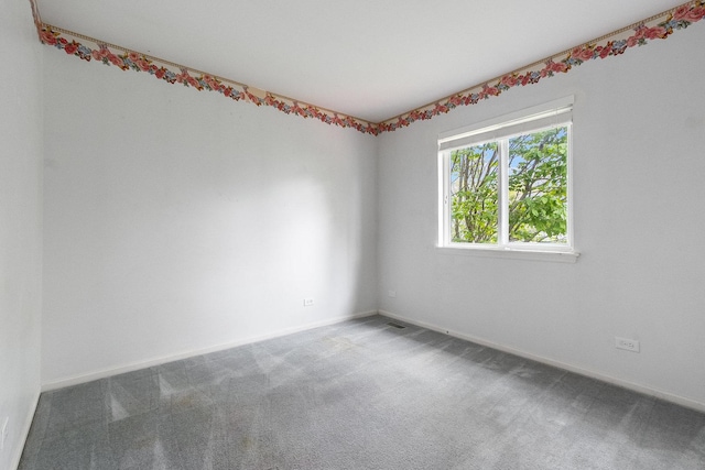 spare room featuring carpet flooring and baseboards