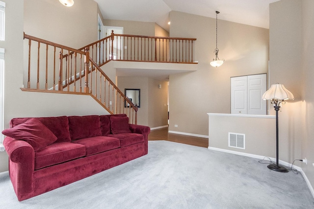 carpeted living room with baseboards, high vaulted ceiling, and stairs