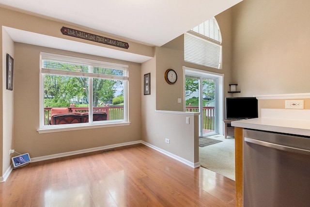 unfurnished dining area featuring healthy amount of natural light, light wood-style floors, and baseboards