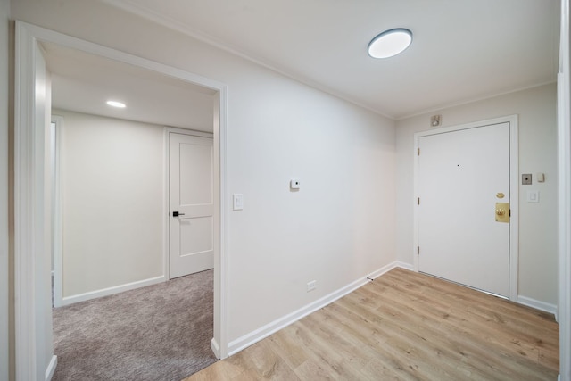 entrance foyer with ornamental molding, light wood-style flooring, and baseboards