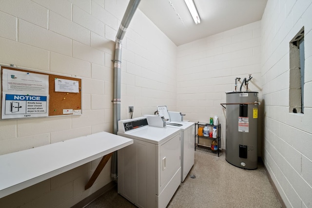 shared laundry featuring electric water heater, washer and dryer, and concrete block wall
