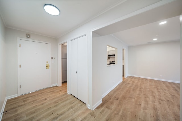 corridor with light wood-style floors, ornamental molding, and baseboards