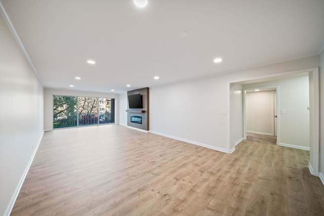 unfurnished living room with light wood-type flooring, baseboards, recessed lighting, a glass covered fireplace, and ornamental molding