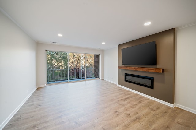 unfurnished living room with a glass covered fireplace, wood finished floors, baseboards, recessed lighting, and ornamental molding