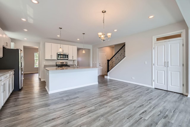 kitchen featuring stainless steel appliances, white cabinetry, a chandelier, light countertops, and light wood-style floors