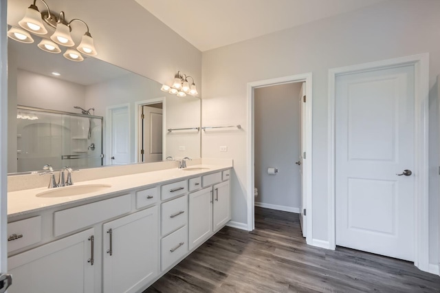 full bath with a stall shower, double vanity, wood finished floors, baseboards, and toilet