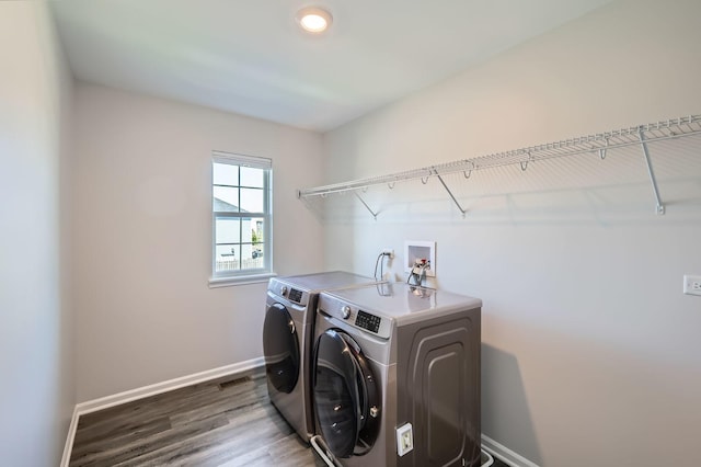 laundry area featuring washing machine and clothes dryer, baseboards, and wood finished floors