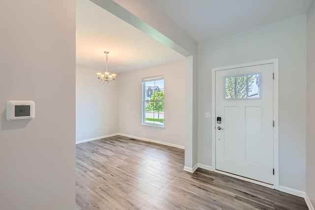 foyer with healthy amount of natural light, a chandelier, wood finished floors, and baseboards