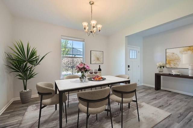 dining area featuring a chandelier, wood finished floors, and baseboards