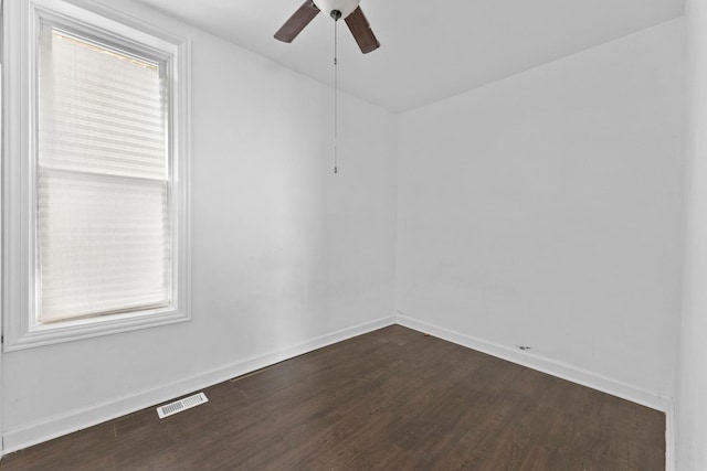 spare room featuring dark wood-style flooring, a ceiling fan, and baseboards