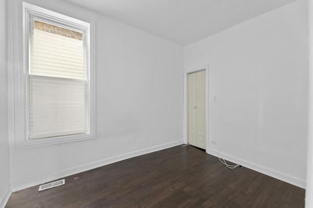 spare room with dark wood-style flooring and baseboards