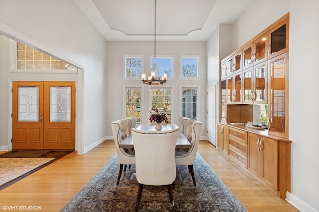 20662 Francisca Way, Frankfort, IL 60423 - dining room with a chandelier, a high ceiling, light wood-style floors, a raised ceiling, and baseboards