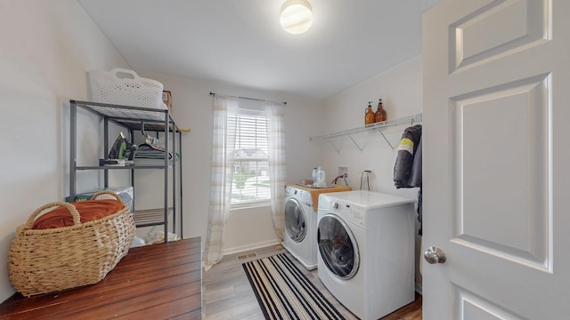washroom with washer and dryer, light wood-type flooring, and baseboards