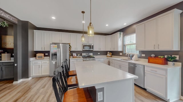 kitchen featuring appliances with stainless steel finishes, light wood-type flooring, a kitchen breakfast bar, a kitchen island, and white cabinets