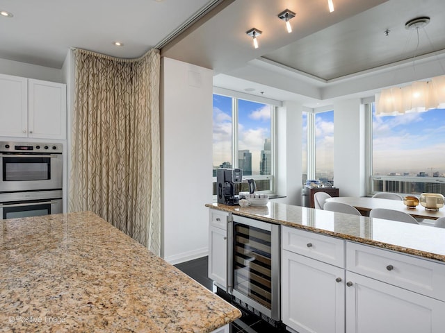 33 W Ontario St Unit 58E, Chicago, IL 60654 - kitchen featuring wine cooler, stainless steel double oven, white cabinetry, recessed lighting, and light stone countertops