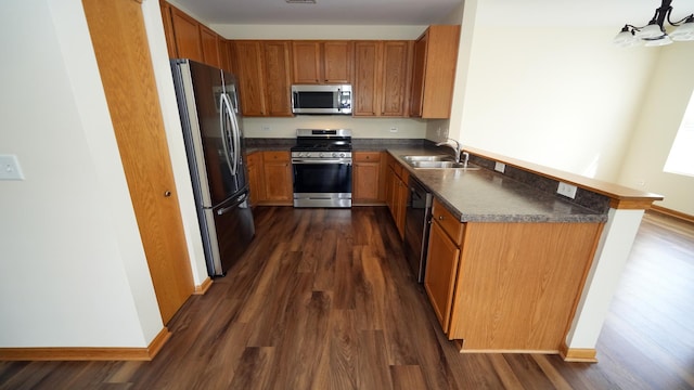 2620 Christie Dr, Algonquin, IL 60102 - kitchen featuring appliances with stainless steel finishes, dark countertops, dark wood-style floors, a sink, and brown cabinetry