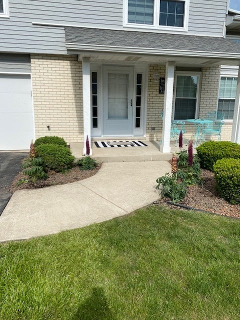 8223 170th St, Tinley Park, IL 60477 - view of exterior entry with brick siding, a garage, a porch, and roof with shingles