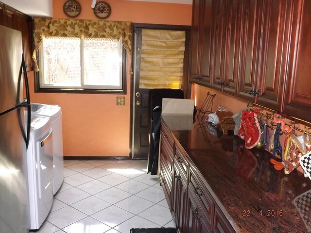 clothes washing area featuring independent washer and dryer, light tile patterned floors, and baseboards