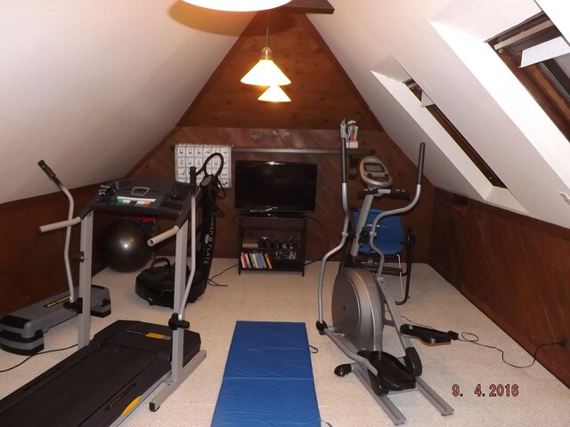 exercise room featuring wooden walls, lofted ceiling, and carpet flooring