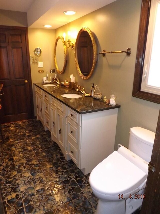 bathroom with toilet, double vanity, and recessed lighting