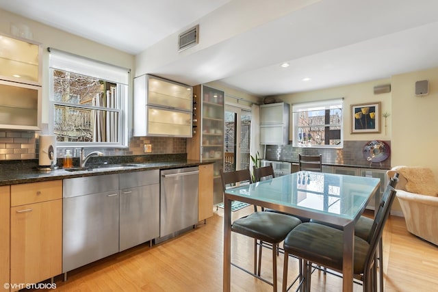 1747 N Fern Ct, Chicago, IL 60614 - kitchen featuring stainless steel dishwasher, a sink, decorative backsplash, light wood-style floors, and glass insert cabinets