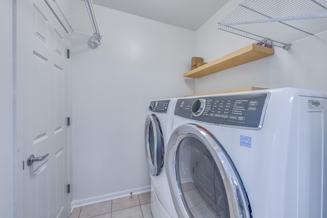 laundry room with washing machine and dryer, light tile patterned floors, and baseboards