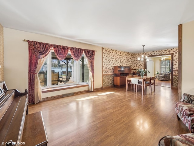 985 W Firestone Dr, Hoffman Estates, IL 60192 - living area featuring a chandelier, wallpapered walls, wood finished floors, an accent wall, and baseboards