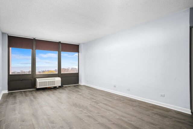 unfurnished room featuring dark wood-style floors, a textured ceiling, baseboards, and a wall mounted AC