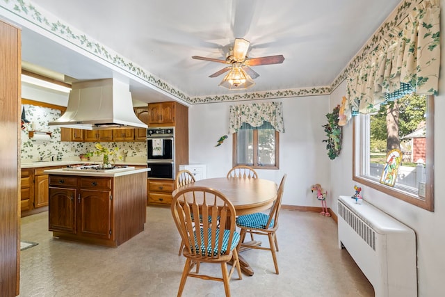 428 Julia St, Lemont, IL 60439 - kitchen featuring island exhaust hood, radiator, white gas cooktop, light countertops, and light flooring