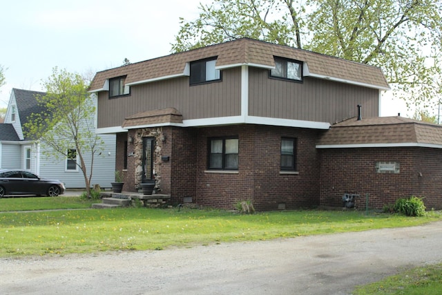 view of front of house featuring a front yard, brick siding, a shingled roof, and mansard roof