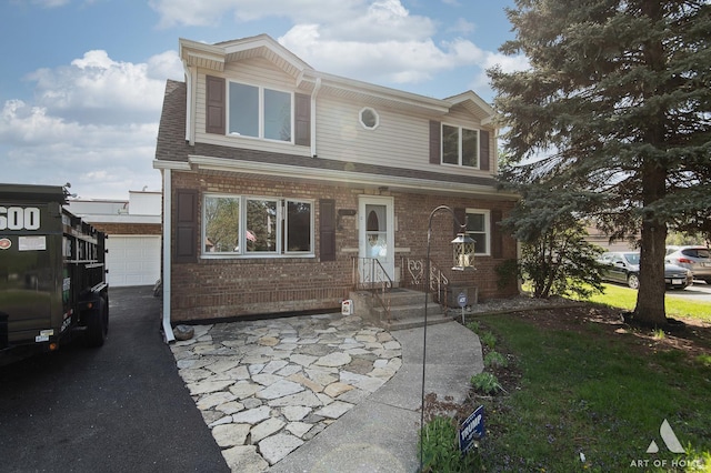 view of front facade featuring brick siding, a shingled roof, and asphalt driveway