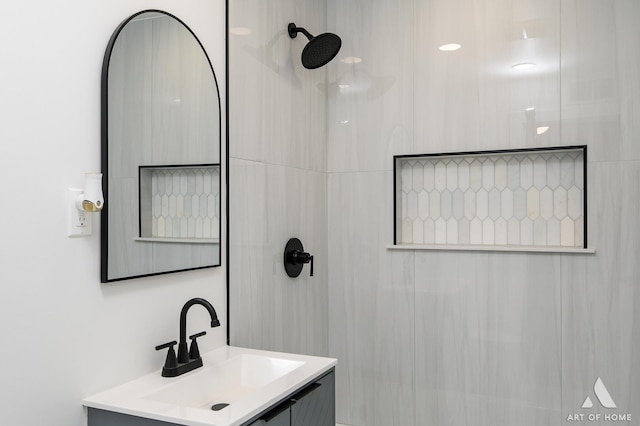 bathroom with a tile shower and vanity