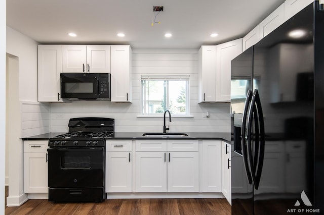 kitchen featuring black appliances, a sink, dark countertops, tasteful backsplash, and white cabinetry