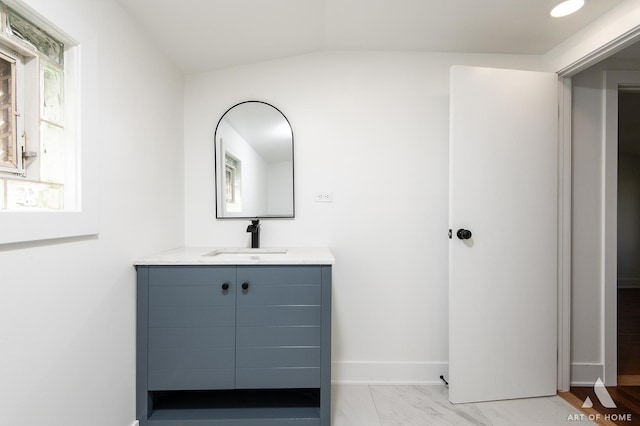 bathroom with baseboards, vanity, and vaulted ceiling