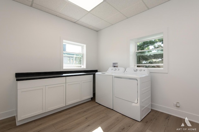 clothes washing area with separate washer and dryer, cabinet space, light wood-type flooring, and plenty of natural light